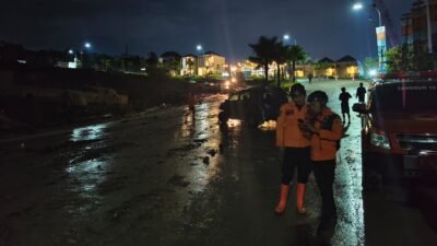 Petugas gabungan dan masyarakat saat melakukan pembersihan material lumpur dan bebatuan yang menutup ruas jalan di Desa Bojong Koneng, Kecamatan Babakan Madang, Rabu (11/2/2026).