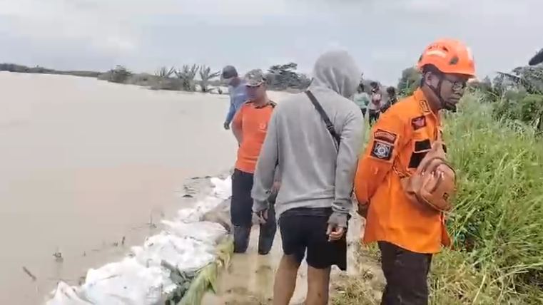 Petugas gabungan melakukan monitoring usai memperkuat tanggul sungai menggunakan kantong berisi pasir di Desa Gubug, Kecamatan Gubug, Kabupaten Grobogan, Jawa Tengah, Senin (16/2).