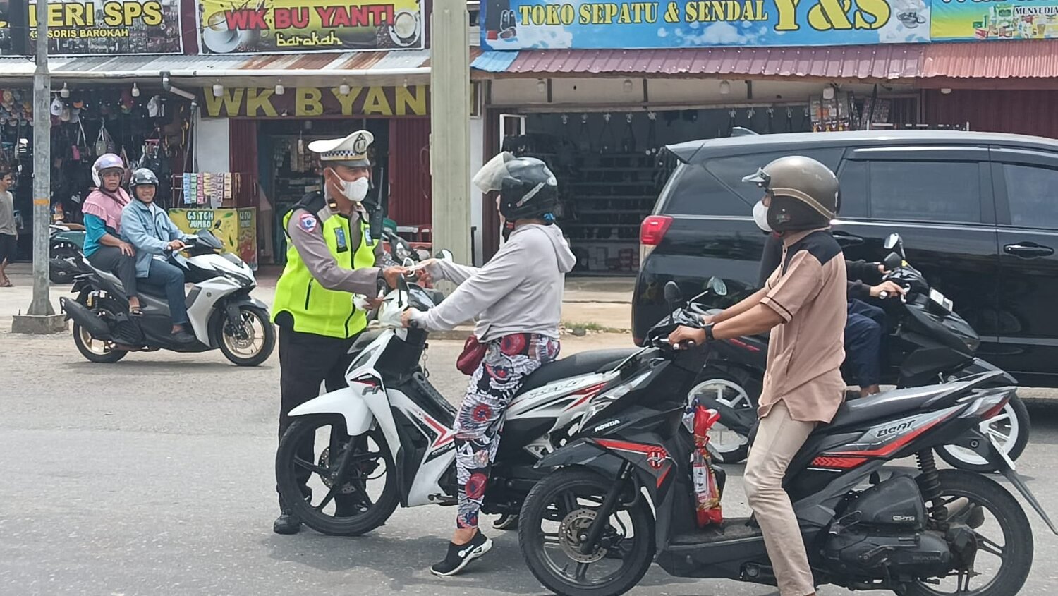 Petugas kepolisian dari Polres Kubu Raya saat memberikan masker kepada pengendara motor di tengah kabut asap guna mengantisipasi dampak buruk penurunan kualitas udara, Selasa (17/2/2026).