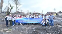 Personel Wingdik 700/Hanud bersama para relawan berfoto bersama membentangkan spanduk bakti sosial di lokasi terdampak erupsi Gunung Semeru yang dipenuhi material vulkanik. (Dok. HO/Faktakalbar.id)