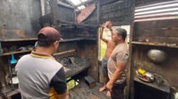 Petugas kepolisian saat melakukan olah tempat kejadian perkara dan memberikan imbauan kepada warga terkait bahaya penggunaan tungku kayu pasca insiden kebakaran rumah di Desa Pelita Jaya, Selasa (10/2/2026).