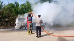 Petugas Polsek dan Damkar memadamkan kebakaran mobil di Entikong akibat bering roda pecah. (Dok: HO/Faktakalbar.id)