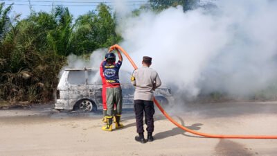 Petugas Polsek dan Damkar memadamkan kebakaran mobil di Entikong akibat bering roda pecah. (Dok: HO/Faktakalbar.id)