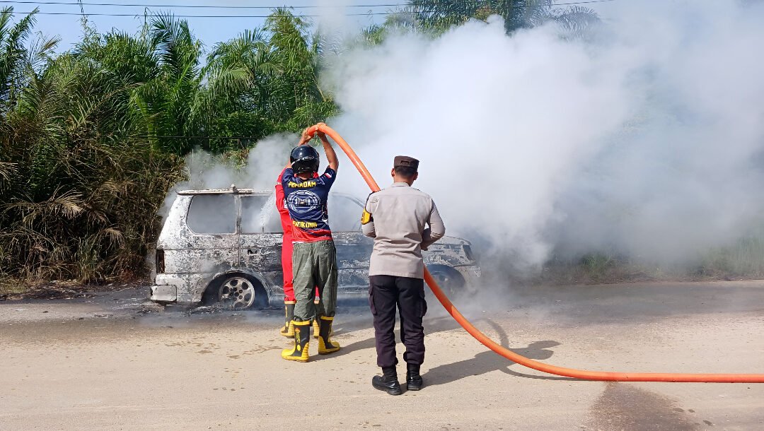 Petugas Polsek dan Damkar memadamkan kebakaran mobil di Entikong akibat bering roda pecah. (Dok: HO/Faktakalbar.id)
