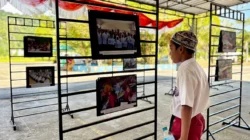 "Seorang pelajar mengamati foto anak-anak dari Desa Pelapis, Kepulauan Karimata, yang sedang belajar di Taman Pendidikan Alquran, pada Pameran Foto Pendidikan dan Kebudayaan di Kantor Dinas Pendidikan Kayong Utara, Selasa (3/2/2026). Pameran foto dirangkai dengan pemberian sepatu dan seragam sekolah untuk siswa kurang mampu."