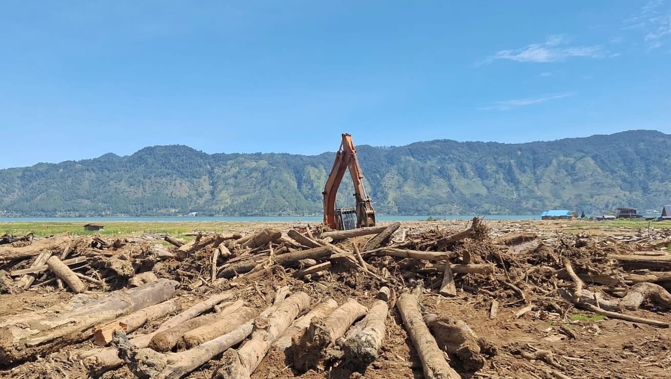 Alat berat dikerahkan untuk membantu pembersihan material potongan kayu yang menutupi areal persawahan pascabanjir di Toweran, Kecamatan Lut Tawar, Kabupaten Aceh Tengah, Provinsi Aceh, Minggu (22/2).