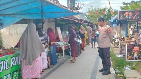 Anggota Polsek Simpang Hilir berdiri memantau situasi keamanan dan aktivitas warga yang berbelanja takjil di Pasar Juadah Teluk Melano. (Dok. HO/Faktakalbar.id)