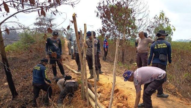Personel Satgas Karhutla Polres Mempawah bergotong royong memperbaiki akses jalan yang terputus menuju lokasi kebakaran lahan gambut di Dusun Telayar, Kecamatan Mempawah Timur.