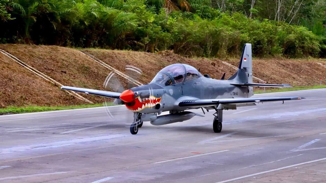 Pesawat tempur taktis EMB-314 Super Tucano milik TNI AU sedang melakukan pendaratan di ruas Jalan Tol Terpeka Simpang Pematang, Lampung, dengan latar belakang pepohonan hijau. (Dok. HO/Faktakalbar.id)