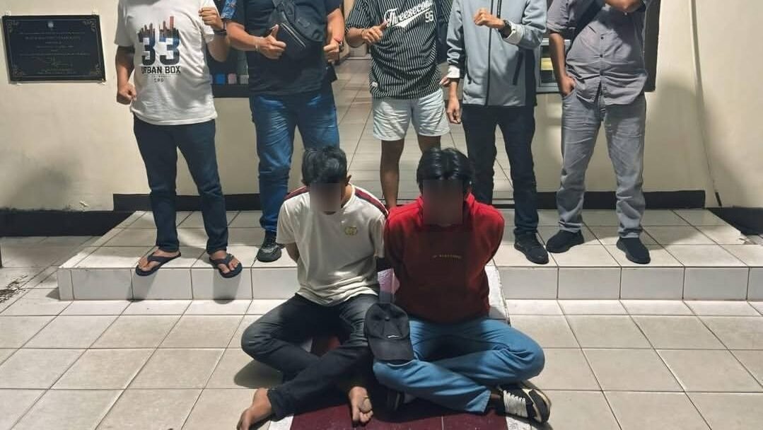 Personel Polsek Pontianak Kota berfoto bersama dua tersangka pelaku pencurian di SD 06 Pontianak Kota yang berhasil diamankan dengan tangan borgol, Rabu (11/2/2026).
