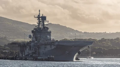 Kapal serbu amfibi USS Iwo Jima (LHD-7) berlabuh di perairan dengan latar belakang perbukitan saat operasi militer berlangsung. (Dok. Ist)