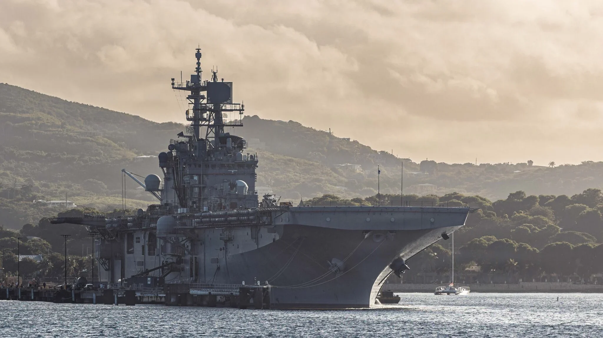 Kapal serbu amfibi USS Iwo Jima (LHD-7) berlabuh di perairan dengan latar belakang perbukitan saat operasi militer berlangsung. (Dok. Ist)