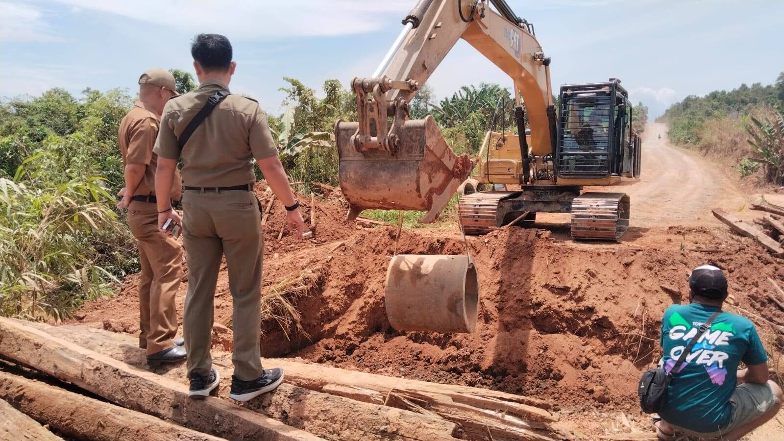 Alat berat ekskavator sedang memasang gorong-gorong untuk perbaikan Jembatan Sedawak yang dipantau oleh Camat Marau. (Dok. HO/Faktakalbar.id)