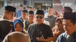 Bupati Kubu Raya Sujiwo mengenakan kacamata hitam berbincang dengan warga saat meninjau paket beras di lokasi Operasi Pasar Desa Teluk Pakedai Dua. (Dok. HO/Faktakalbar.id)