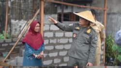 Bupati Kubu Raya Sujiwo mengenakan caping saat meninjau proses pembangunan dinding rumah Ibu Serina di Desa Kuala Dua. (Dok. HO/Faktakalbar.id)