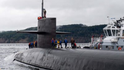 Kapal selam rudal jelajah bertenaga nuklir USS Ohio (SSGN 726) milik Angkatan Laut AS bersandar di pangkalan laut dengan sejumlah kru di atas lambung kapal. (Dok. HO/Faktakalbar.id)