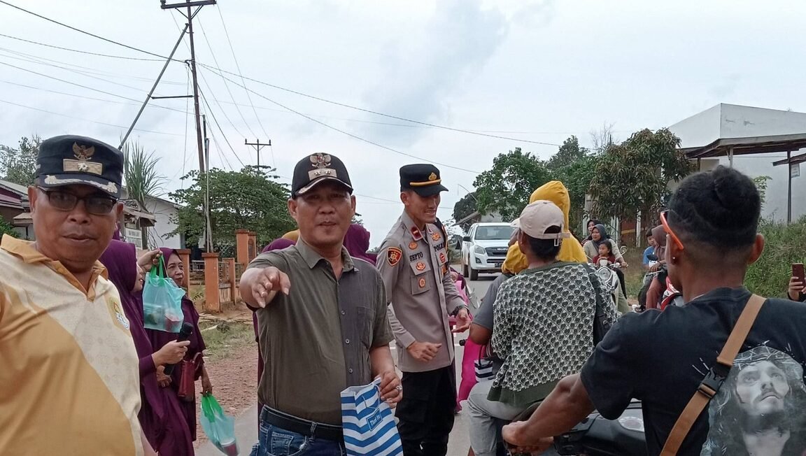 Sekretaris Kecamatan Marau Esau Londong dan personel Polsek Marau membagikan takjil gratis kepada pengendara motor. (Dok. HO/Faktakalbar.id)
