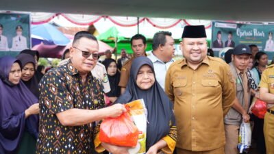 Bupati Melawi Dadi Sunarya Usfa Yursa mendampingi perwakilan Bank Kalbar saat menyerahkan paket sembako murah kepada warga di lokasi Operasi Pasar. (Dok. HO/Faktakalbar.id)