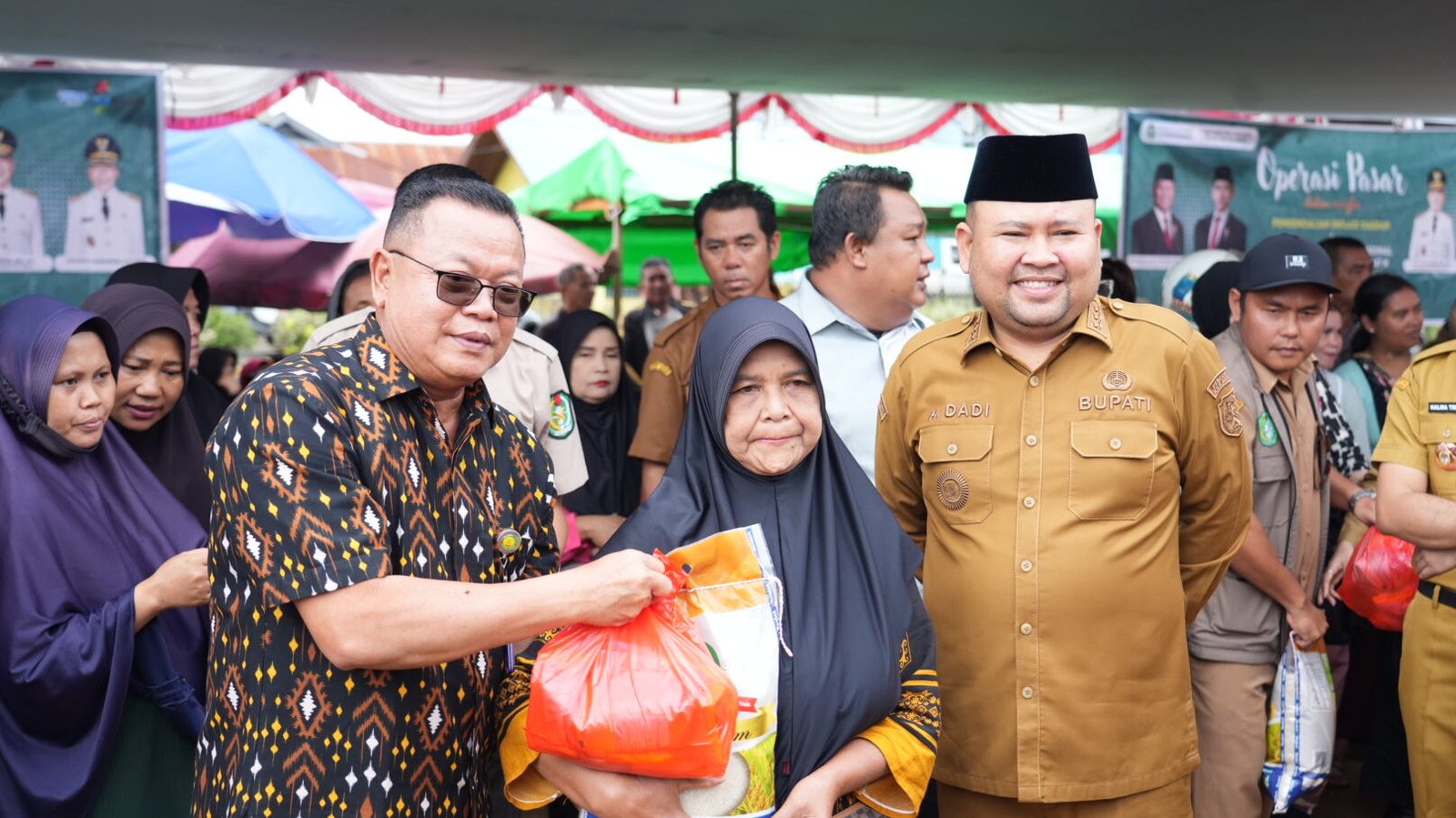 Bupati Melawi Dadi Sunarya Usfa Yursa mendampingi perwakilan Bank Kalbar saat menyerahkan paket sembako murah kepada warga di lokasi Operasi Pasar. (Dok. HO/Faktakalbar.id)