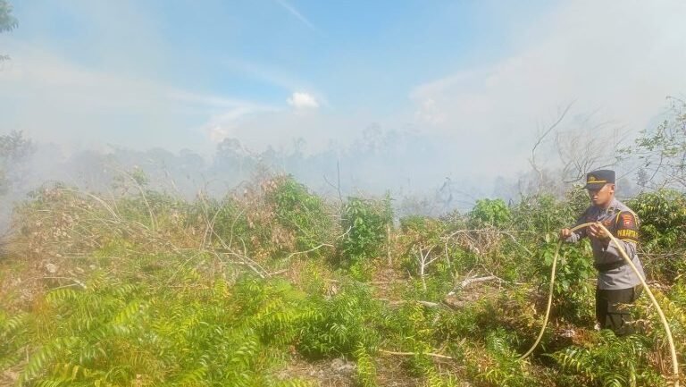 Aparat kepolisian memadamkan titik api di dekat kawasan permukiman. (Dok. Ist)