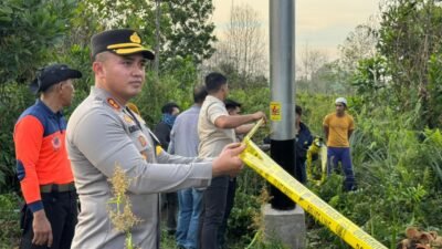 Petugas kepolisian dari Polres Kubu Raya memasang garis polisi di area lahan gambut yang terbakar guna mengamankan tempat kejadian perkara.