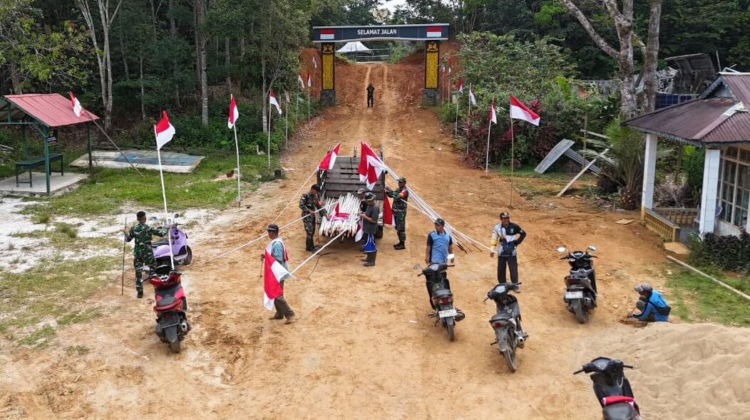 Babinsa Sertu Dwi Ariyanto bersama warga saat bergotong royong menghias permukiman dengan atribut kebangsaan di wilayah perbatasan Desa Temajuk.