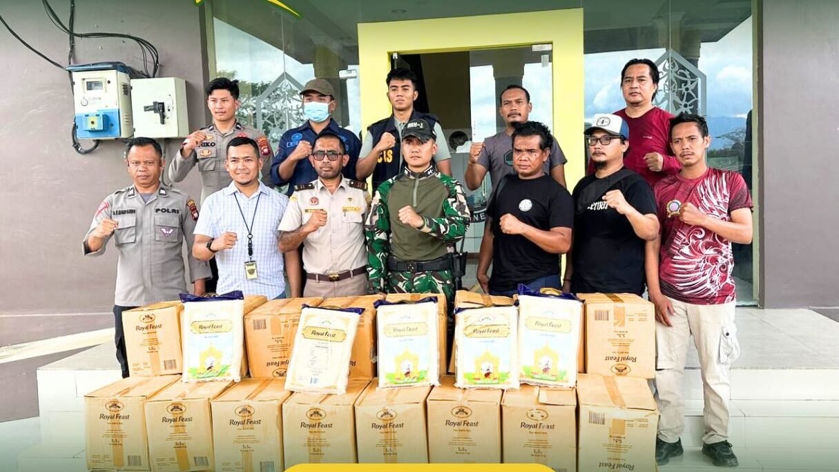 Tim gabungan Karantina Kalbar, TNI, dan Polri berdiri di depan tumpukan kotak beras ilegal merek Royal Feast hasil sitaan di PLBN Entikong. (Dok. HO/Faktakalbar.id)