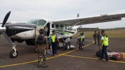 Personel Satgas Yon Parako 466 Pasgat dan Satgas Yonif 403 bersiaga mengamankan proses pendaratan pesawat perintis pembawa logistik warga.