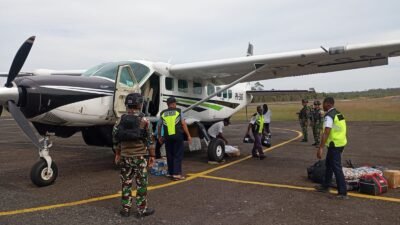 Personel Satgas Yon Parako 466 Pasgat dan Satgas Yonif 403 bersiaga mengamankan proses pendaratan pesawat perintis pembawa logistik warga.