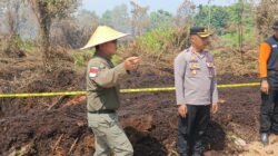 Personel Satreskrim Polres Kubu Raya memasang garis polisi di lokasi kebakaran lahan di Sungai Raya Dalam untuk keperluan penyelidikan, Kamis (26/3/2026).