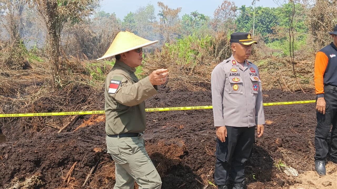 Personel Satreskrim Polres Kubu Raya memasang garis polisi di lokasi kebakaran lahan di Sungai Raya Dalam untuk keperluan penyelidikan, Kamis (26/3/2026).