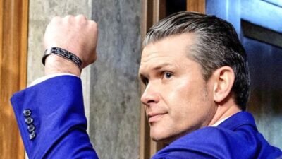Potret Secretary of War Pete Hegseth mengenakan jas biru mengangkat kepalan tangan. (Dok. Ist)