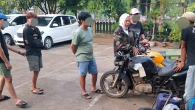 Pihak kepolisian saat mengamankan barang bukti berupa sepeda motor bertangki siluman dan belasan jerigen dalam operasi penggerebekan BBM ilegal.