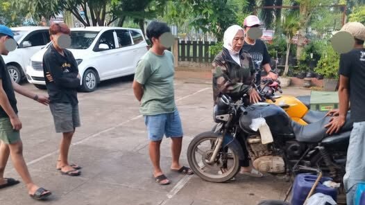 Pihak kepolisian saat mengamankan barang bukti berupa sepeda motor bertangki siluman dan belasan jerigen dalam operasi penggerebekan BBM ilegal.