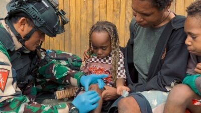 Seorang prajurit medis dari Satgas Yon Parako 466 saat memberikan penanganan medis kepada seorang anak di kawasan permukiman pedalaman Wamena, Papua.