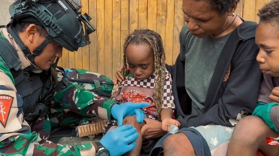 Seorang prajurit medis dari Satgas Yon Parako 466 saat memberikan penanganan medis kepada seorang anak di kawasan permukiman pedalaman Wamena, Papua.