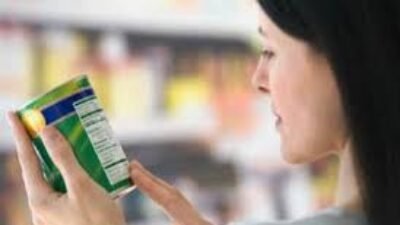 Seorang perempuan muda sedang meneliti label informasi gizi pada kemasan minuman ringan sebelum memutuskan untuk membelinya di swalayan.