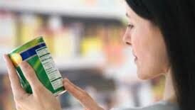 Seorang perempuan muda sedang meneliti label informasi gizi pada kemasan minuman ringan sebelum memutuskan untuk membelinya di swalayan.