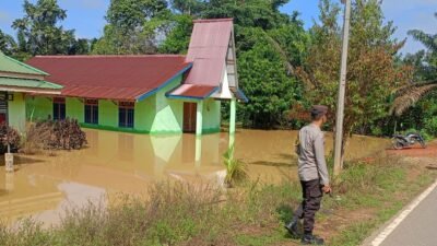 Aparat kepolisian dari Polsek Toba saat meninjau langsung kondisi banjir yang merendam akses jalan dan belasan rumah warga di Desa Bagan Asam.