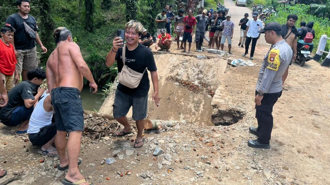 Kondisi sebagian badan jalan pada jembatan di Kecamatan Meliau yang ambruk tergerus air dan mengakibatkan sebuah truk terperosok ke dalam lubang.