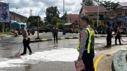 Personel gabungan dari kepolisian dan pemadam kebakaran saat membersihkan permukaan jalan aspal dari genangan bahan bakar solar di kawasan Tugu PKK.