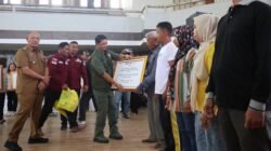 Kepala BNPB Letjen TNI Suharyanto (baju rompi hijau) menyerahkan dana stimulan perbaikan rumah secara simbolis kepada warga terdampak bencana hidrometeorologi basah akibat Siklon Senyar di Gedung GOR Pandan, Sibolga, Tapanuli Tengah, Selasa (21/4).