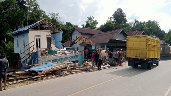 Alat berat ekskavator bersiaga bersama aparat keamanan dan warga setempat saat mengevakuasi sisa bangunan dalam proses pembersihan puing rumah yang amblas di Dusun Gonis Tekam.