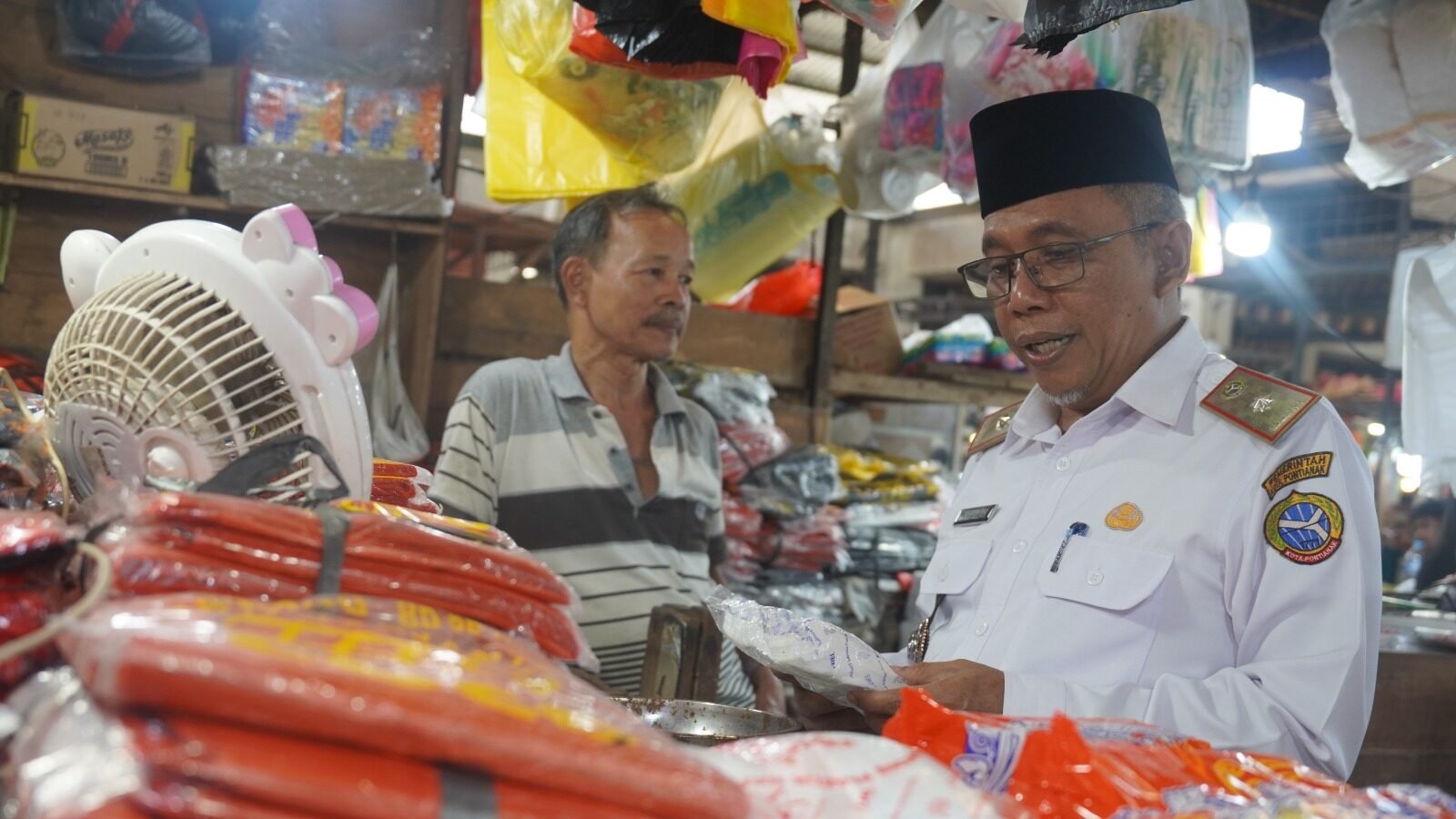 Sekretaris Daerah Kota Pontianak, Amirullah, sedang berdialog dengan pedagang dan mengecek langsung harga barang kemasan plastik saat melakukan peninjauan di Pasar Flamboyan pasca Idulfitri. (Dok. HO/Faktakalbar.id)