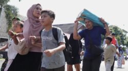 Warga termasuk ibu dan anak-anak bergegas menyusuri jalan menuju lokasi pengungsian sambil membawa perlengkapan darurat dalam simulasi evakuasi bencana banjir sebagai bagian dari puncak peringatan HKB 2026 di Kecamatan Baiturrahman, Kota Banda Aceh, Minggu (26/4).