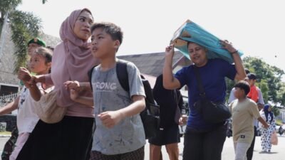 Warga termasuk ibu dan anak-anak bergegas menyusuri jalan menuju lokasi pengungsian sambil membawa perlengkapan darurat dalam simulasi evakuasi bencana banjir sebagai bagian dari puncak peringatan HKB 2026 di Kecamatan Baiturrahman, Kota Banda Aceh, Minggu (26/4).