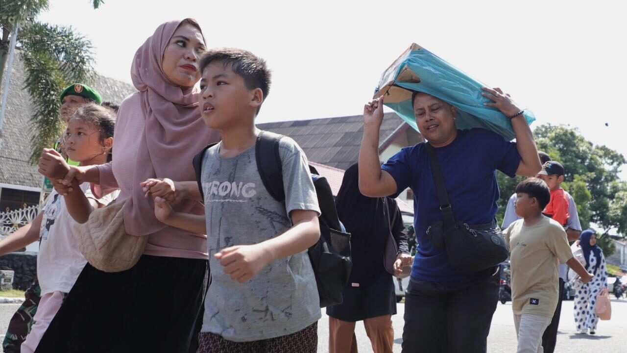 Warga termasuk ibu dan anak-anak bergegas menyusuri jalan menuju lokasi pengungsian sambil membawa perlengkapan darurat dalam simulasi evakuasi bencana banjir sebagai bagian dari puncak peringatan HKB 2026 di Kecamatan Baiturrahman, Kota Banda Aceh, Minggu (26/4).
