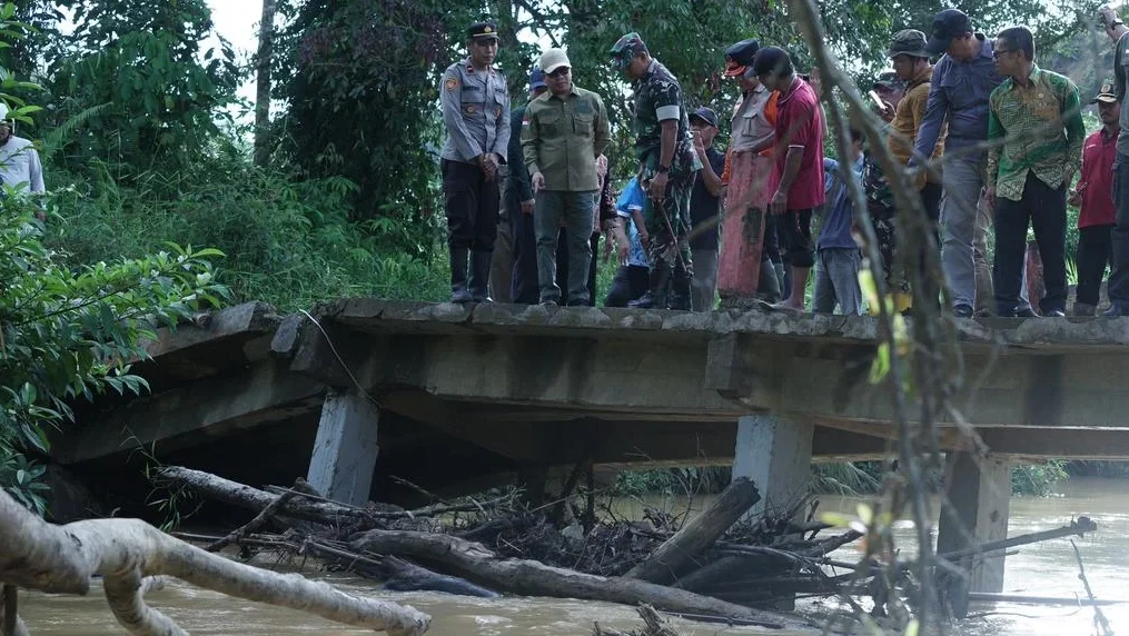 Bupati Sambas Satono didampingi Dandim 1208/Sambas memantau kondisi struktur Jembatan Berkemajuan yang miring setelah diterjang arus sungai deras.