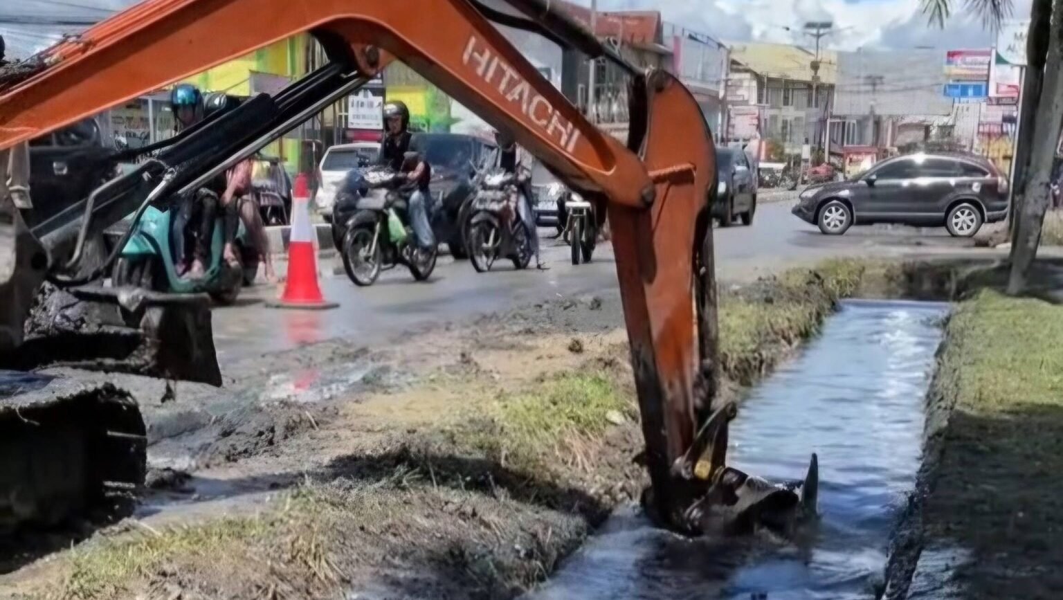 Alat berat milik Dinas Lingkungan Hidup Kabupaten Sintang mengeruk endapan lumpur dan sampah dari drainase yang memicu genangan di kawasan jalan raya.