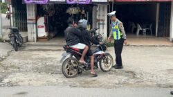 Personel kepolisian lalu lintas memberikan teguran dan penindakan kepada pengendara sepeda motor yang melanggar aturan kelengkapan berkendara di jalan raya.